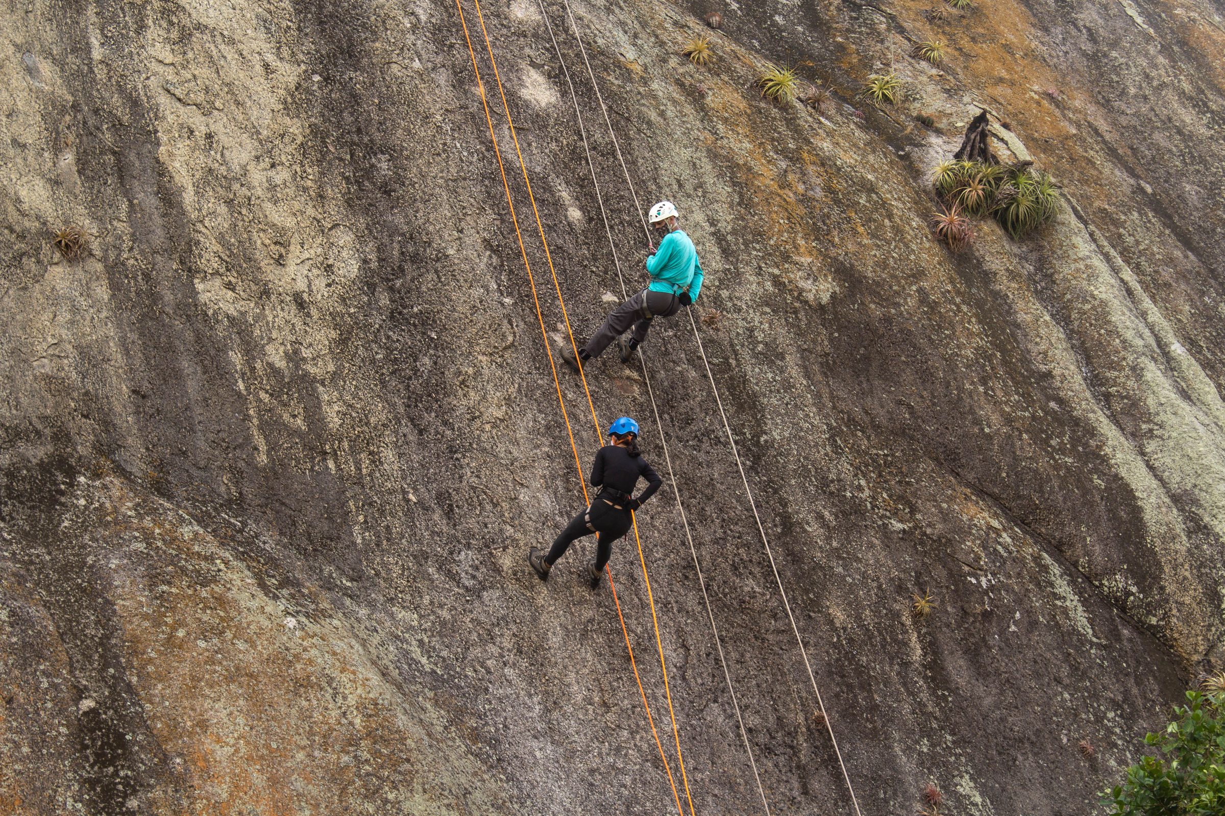 Two climbers abseiling a steep granite slab